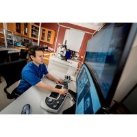 Man in blue shirt working at a computer with large screen monitor