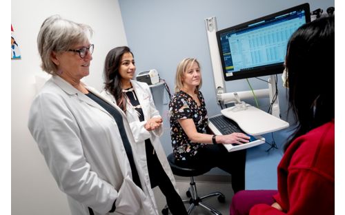 three doctors and a patient in an exam room