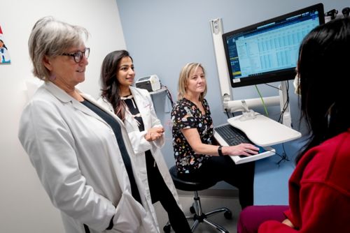 three doctors and a patient in an exam room