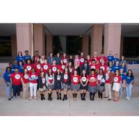 Group of people in red shirts posing for a photo in front of a building