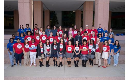 Group of people in red shirts posing for a photo in front of a building