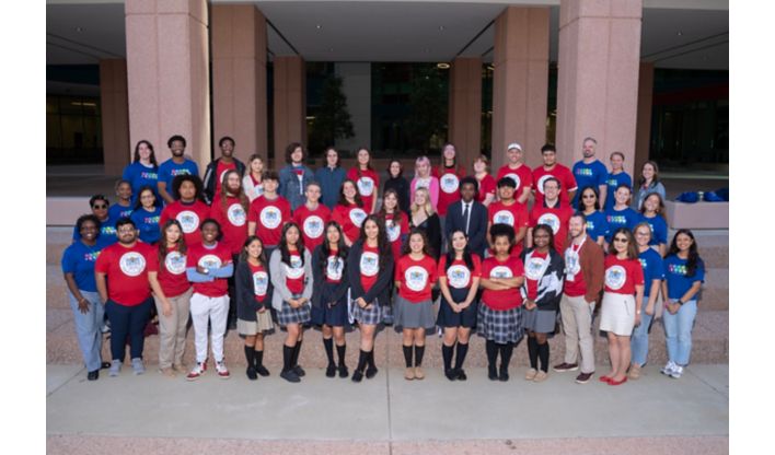 Group of people in red shirts posing for a photo in front of a building