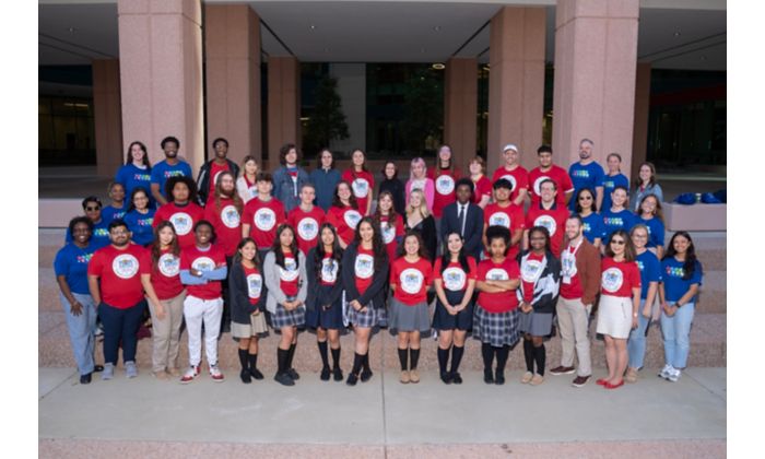 Group of people in red shirts posing for a photo in front of a building