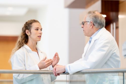 Woman and man in white coats talking in a hallway