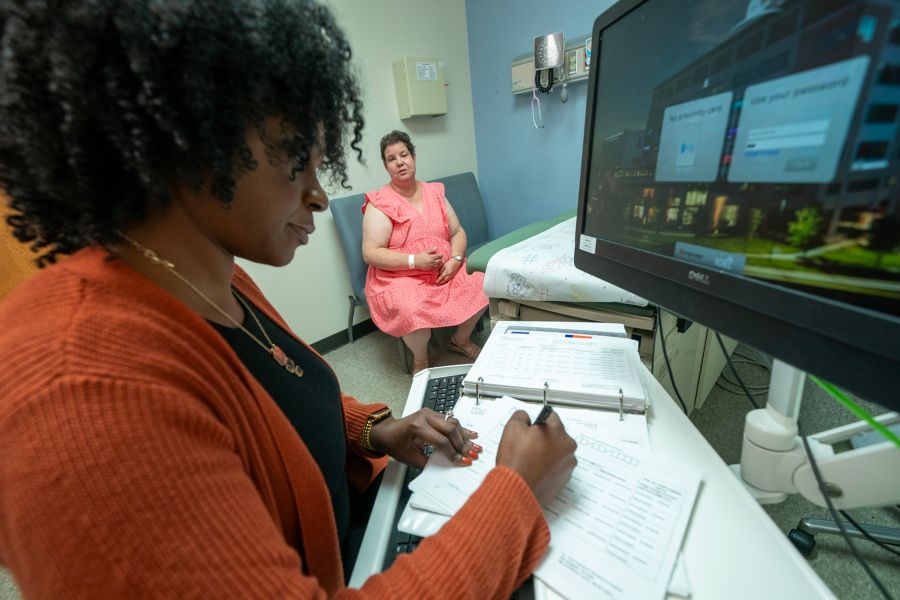 Female staff writing in notebook while looking at computer monitor
