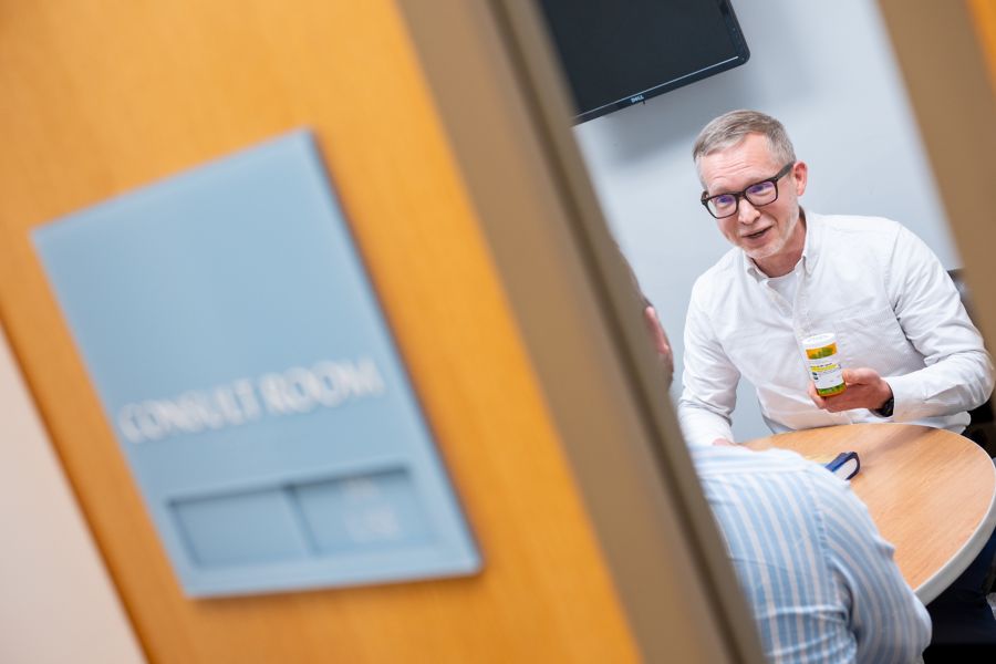 pharmacist in consult room holding medication bottle