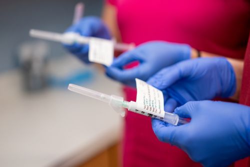 Gloved hands holding syringes