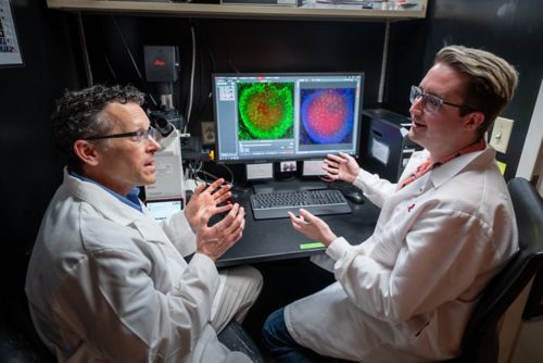 Mark Hatley talking to another man in front of a computer screen