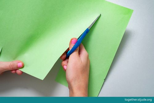 Cutting a straight line into construction paper using scissors