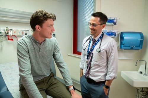 Evan Moore talks with Matthew Ehrhardt, MD, during a checkup.
