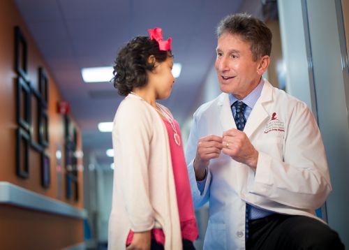 Care team member in a hallway kneeling down next to a young patient