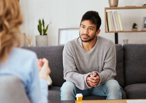 A Man sitting on a couch talking to someone