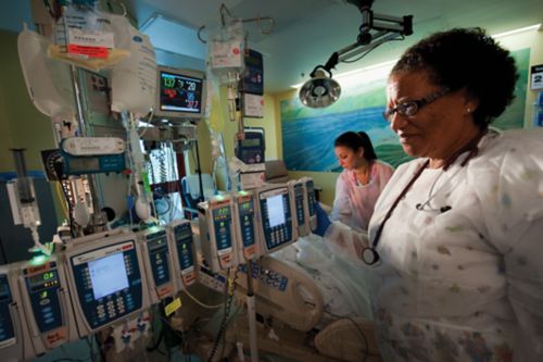 Care team member standing in front of a collection of chemotherapy infusion pumps.