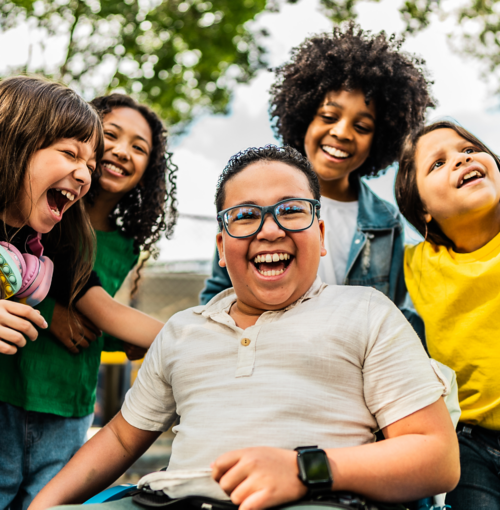 Diverse group of happy elementary school children smiling and laughing together outdoors, multicultural kids showing joy and friendship in natural setting
