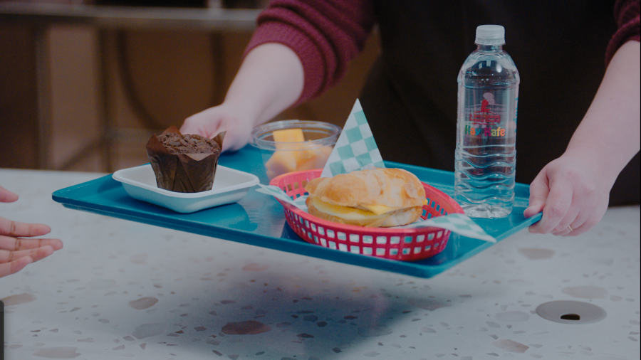 Person carrying tray of food in cafeteria