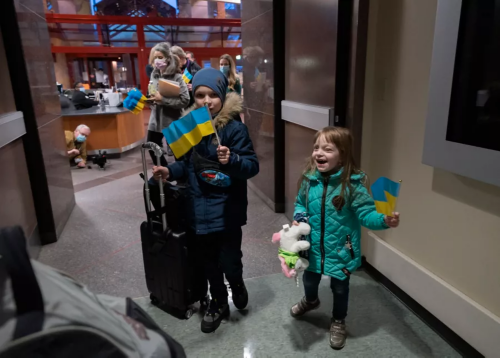 Two siblings waving Ukrainian flag