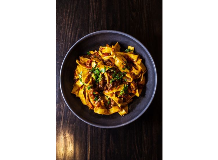 Pappardelle pasta dish with red sauce and green herbs