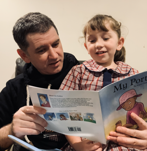 Angus reading a book he authored and illustrated to his daughter Jane