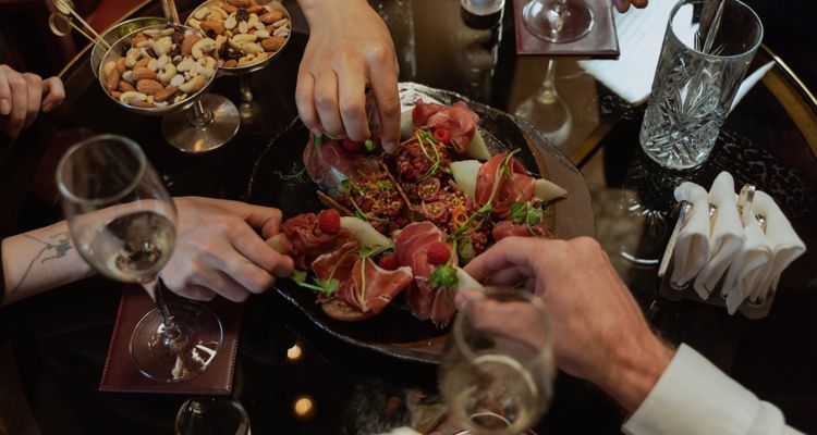 Photo of hands of people diving into plate of appetizers