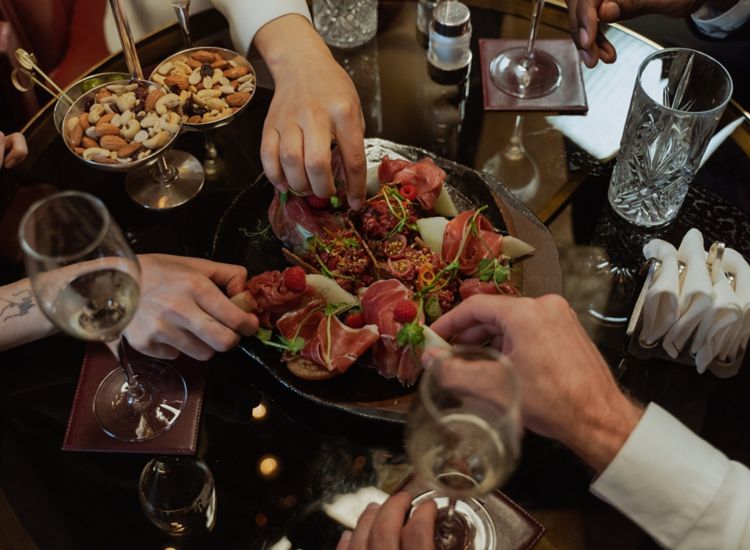 Photo of hands of people diving into plate of appetizers