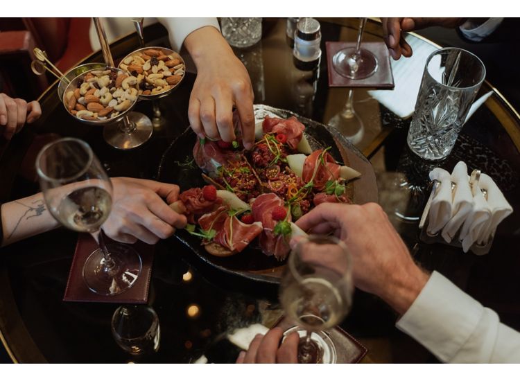 Photo of hands of people diving into plate of appetizers