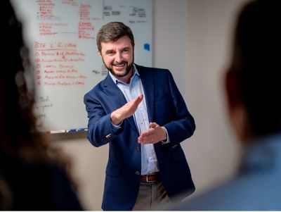 photo of Gregory Armstrong in front of a white board with lots of writing on it.