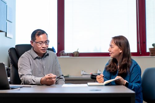 photo of two people talking at a desk.