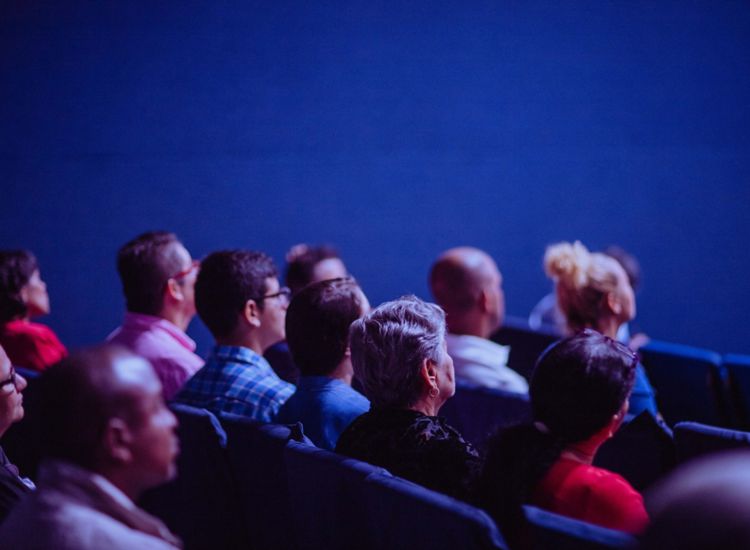 Audience watching a performance in a blue room.