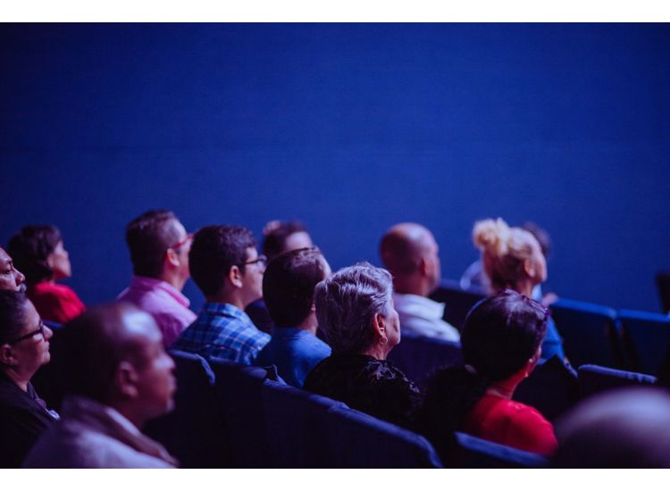 Audience watching a performance in a blue room.