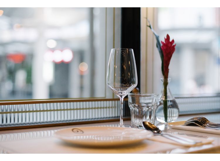 photo of place setting with wine glass, red flower in vase