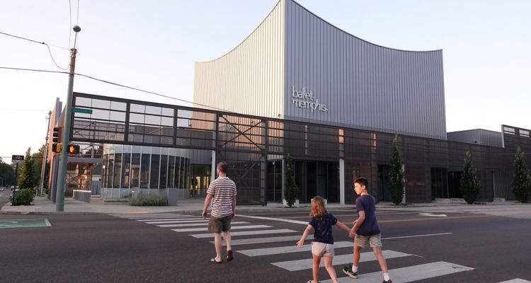 Exterior of Ballet Memphis, modern style building, young family walks across the street holding hands at sunset.