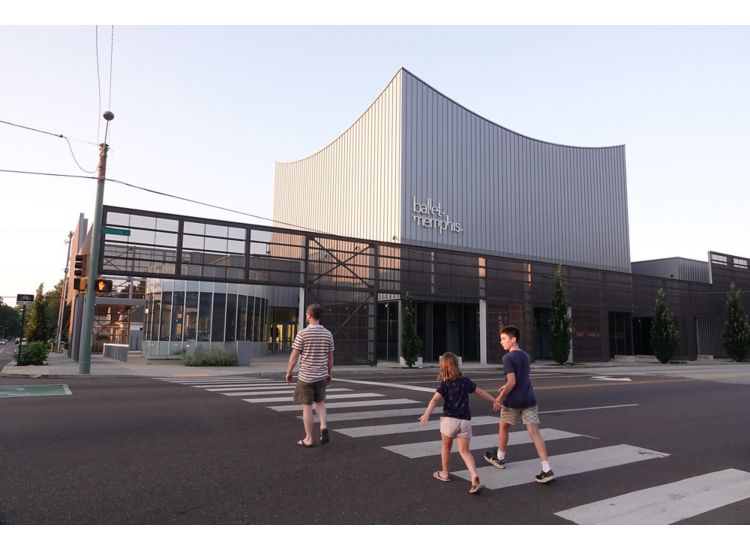 Exterior of Ballet Memphis, modern style building, young family walks across the street holding hands at sunset.