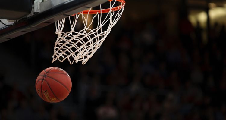 Close up of a basket ball going through a hoop.