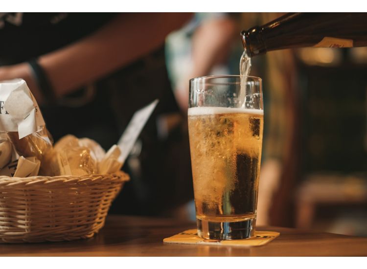 Golden beer being poured into a glass at a bar.