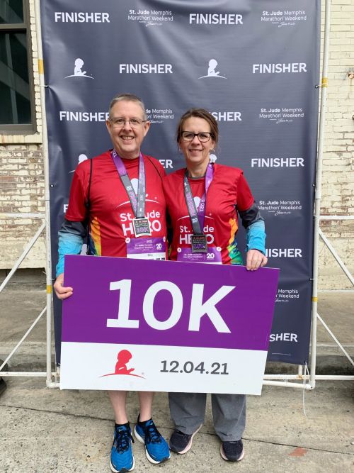 Billy and his wife hold a 10K sign at a race