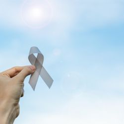 Woman holding gray ribbon for Brain Tumor Awareness Month