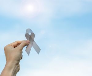 Woman holding gray ribbon for Brain Tumor Awareness Month