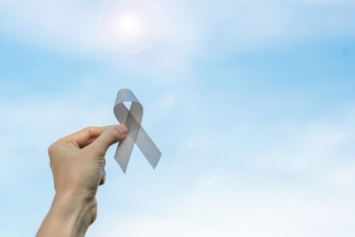 Woman holding gray ribbon for brain tumor awareness month