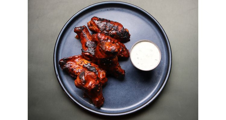 Chicken wings and sauce on a black plate at The Gray Canary Restaurant in Memphis.