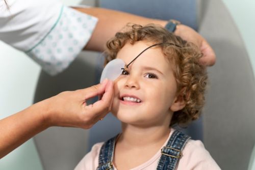 Доктор накладывает повязку на глаз маленькой девочке