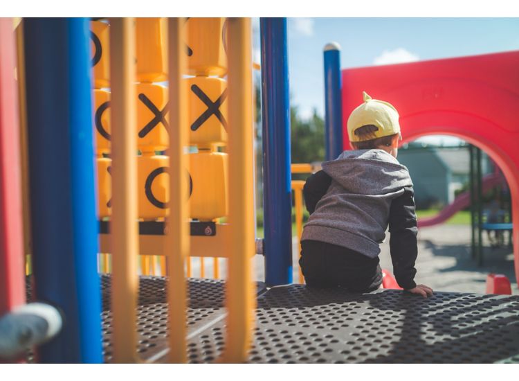 H44  Young child playing on playground structure, preparing to go down a slide.