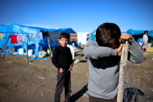 Un niño triste esconde su cara en un campamento de refugiados