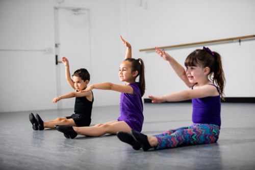 Three small children moving together during dance class.