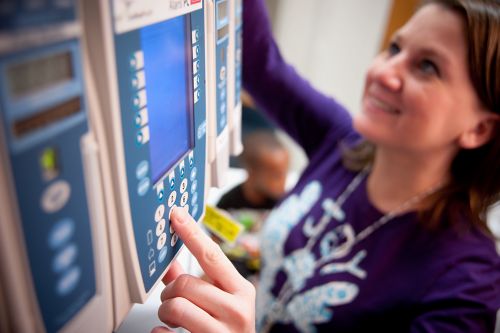 Nurse adjusts settings for pediatric cancer patient in ICU