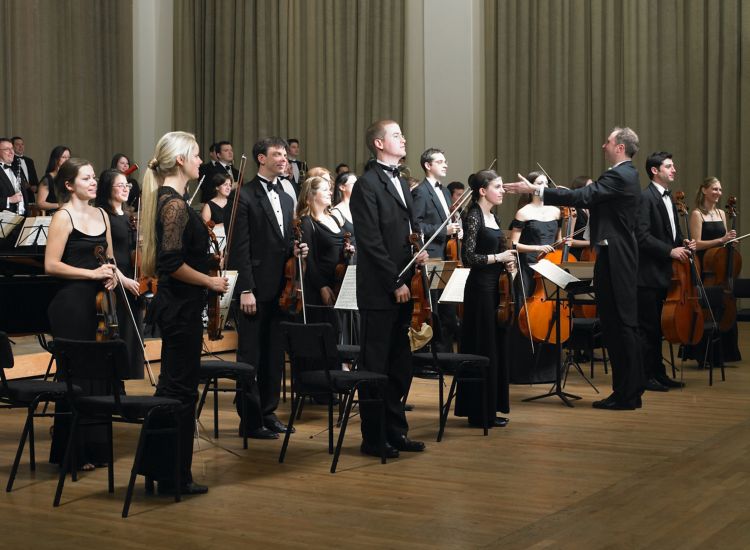 Orchestra members standing before performance