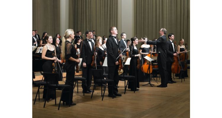 Orchestra members standing before performance