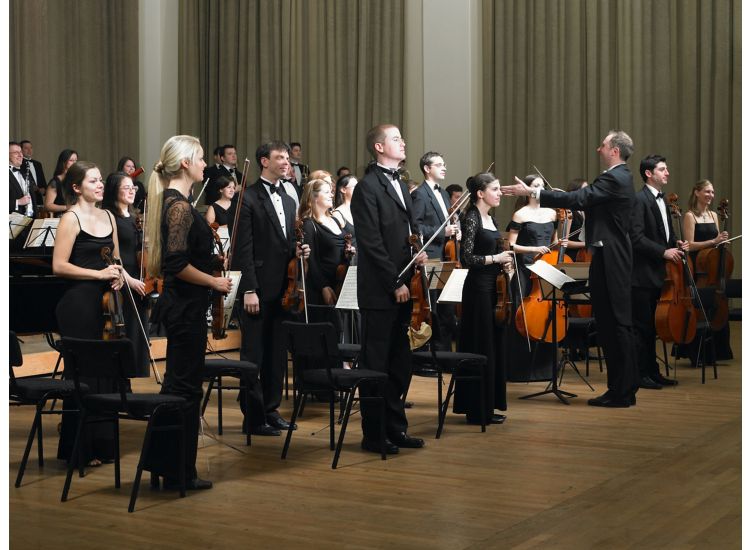 Orchestra members standing before performance