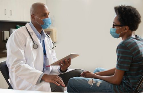 Médico de sexo masculino hablando con un paciente de sexo masculino en un entorno clínico