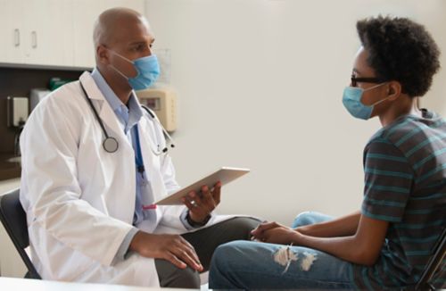 Male doctor talking to male patient in clinical setting