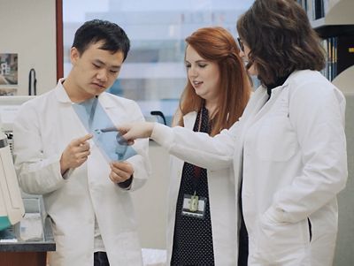 three people in white coats discussing something